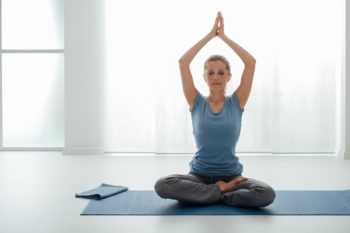 Woman sitting on yoga mat doing yoga